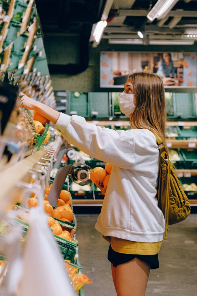 Woman wearing mask choosing oranges in a supermarket during the pandemic.