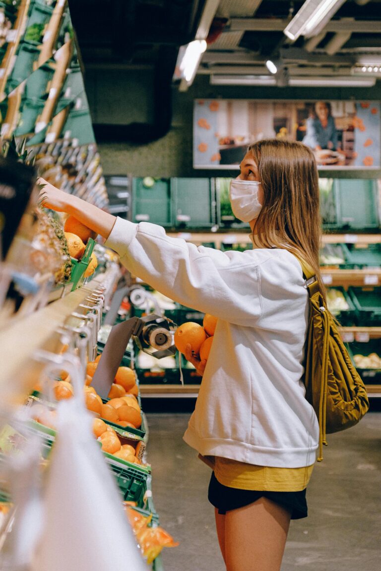 Woman wearing mask choosing oranges in a supermarket during the pandemic.